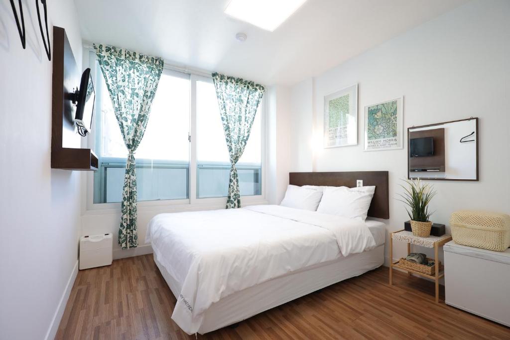 釜山Ekonomy Haeundae Hostel的白色的卧室设有一张大床和一个窗户