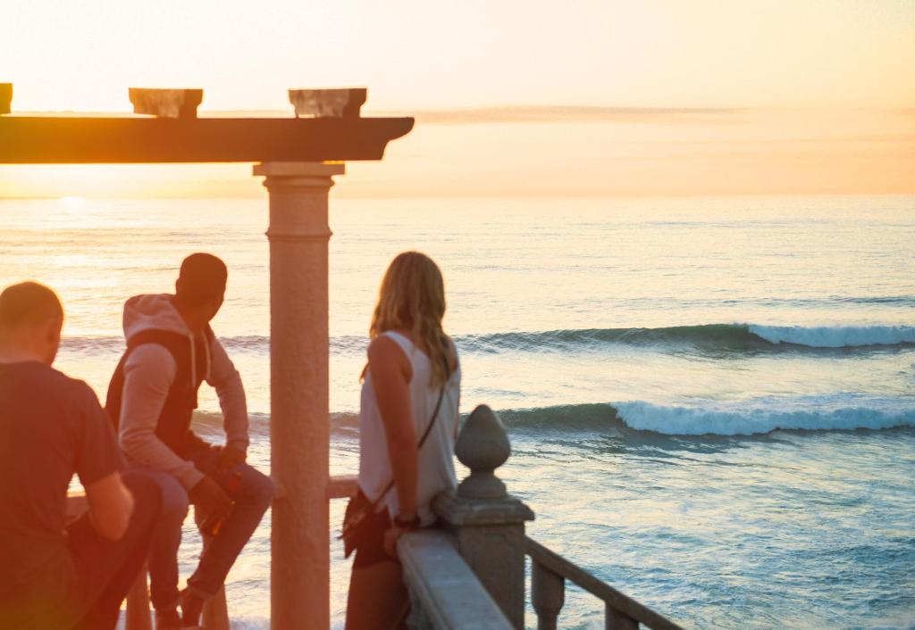 埃里塞拉Laneez Ericeira Surf House的一群人坐在码头上,看着大海