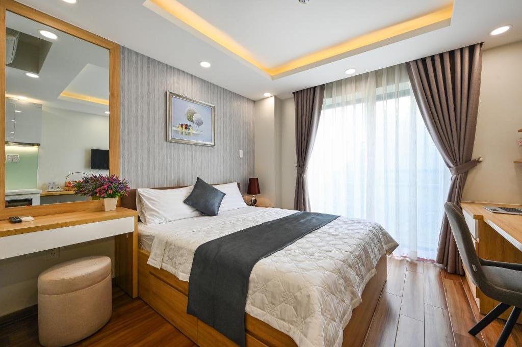 胡志明市Nikko Hotel - The Classy Life的一间卧室配有一张床、一张书桌和一面镜子