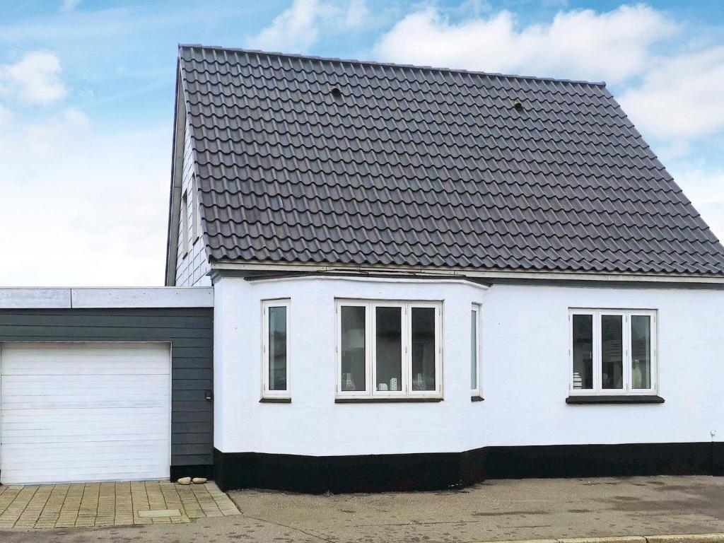 曲博伦Holiday home Thyborøn IV的一间白色的房子,有黑色的屋顶和一个车库