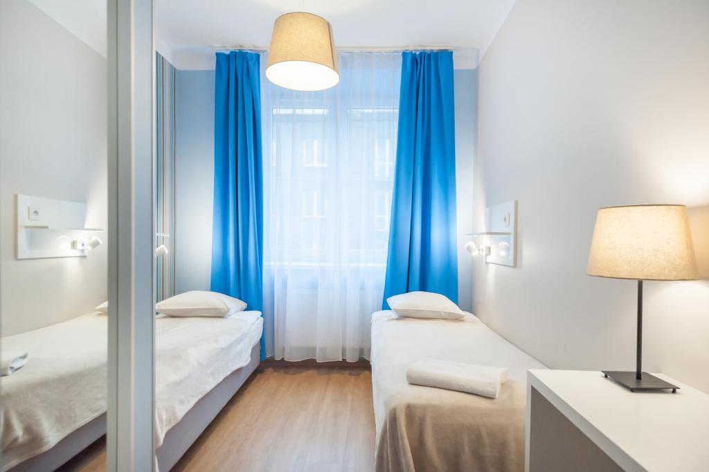 克拉科夫普瑞米安旅馆的客房设有两张床和一扇带蓝色窗帘的窗户。