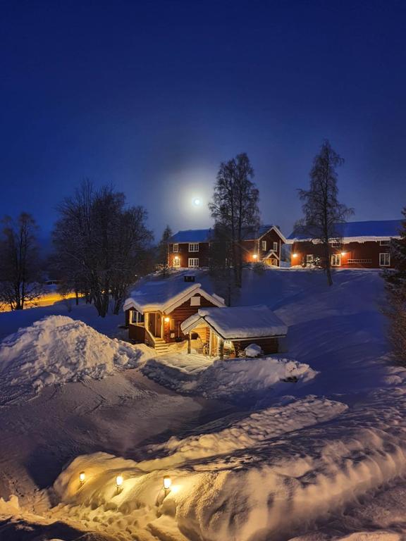 萨伦Backamgården的夜晚有雪覆盖的房子