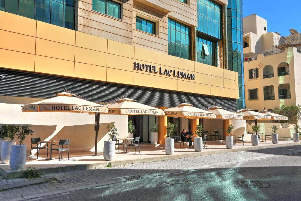 突尼斯莱芒湖酒店的大楼前有桌子和遮阳伞的酒店
