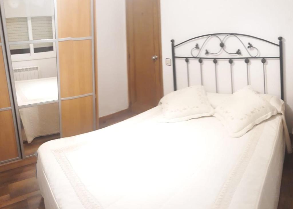 奥伦塞Enseñanza的一间卧室配有一张带白色床单和镜子的床