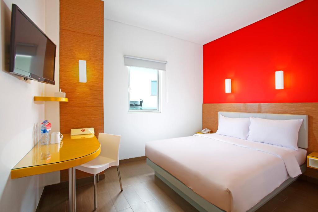 库塔日落大道巴厘岛爱玛黎丝酒店的一间卧室配有一张床和一张书桌及电视