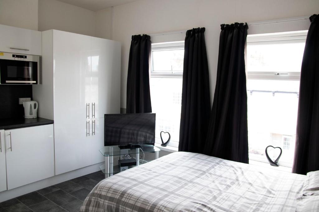 克利索普斯Bursar Street 19的一间卧室配有黑色窗帘、一张床和电视。
