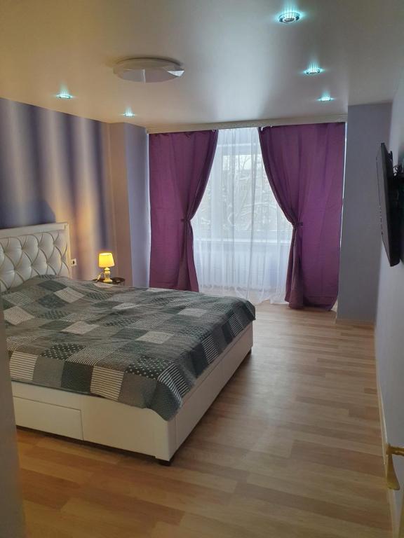 纳尔瓦Kreenholm apartments的一间卧室配有一张床和紫色窗帘