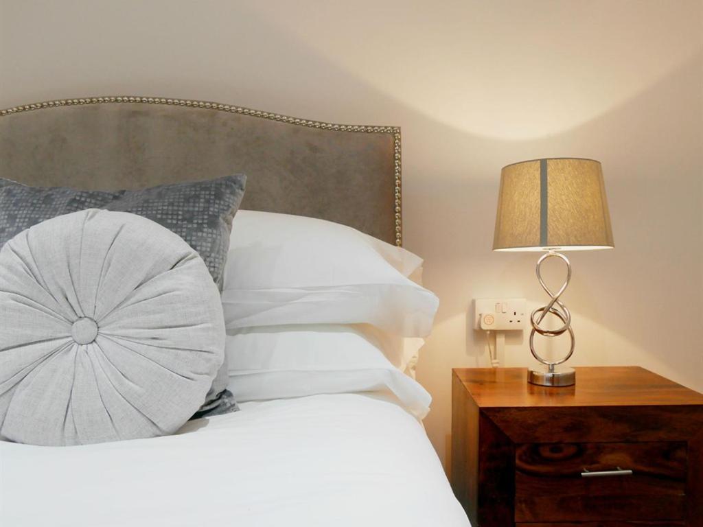 斯旺西曼波斯诺顿之家酒店的一张带枕头的床和床头柜上的台灯