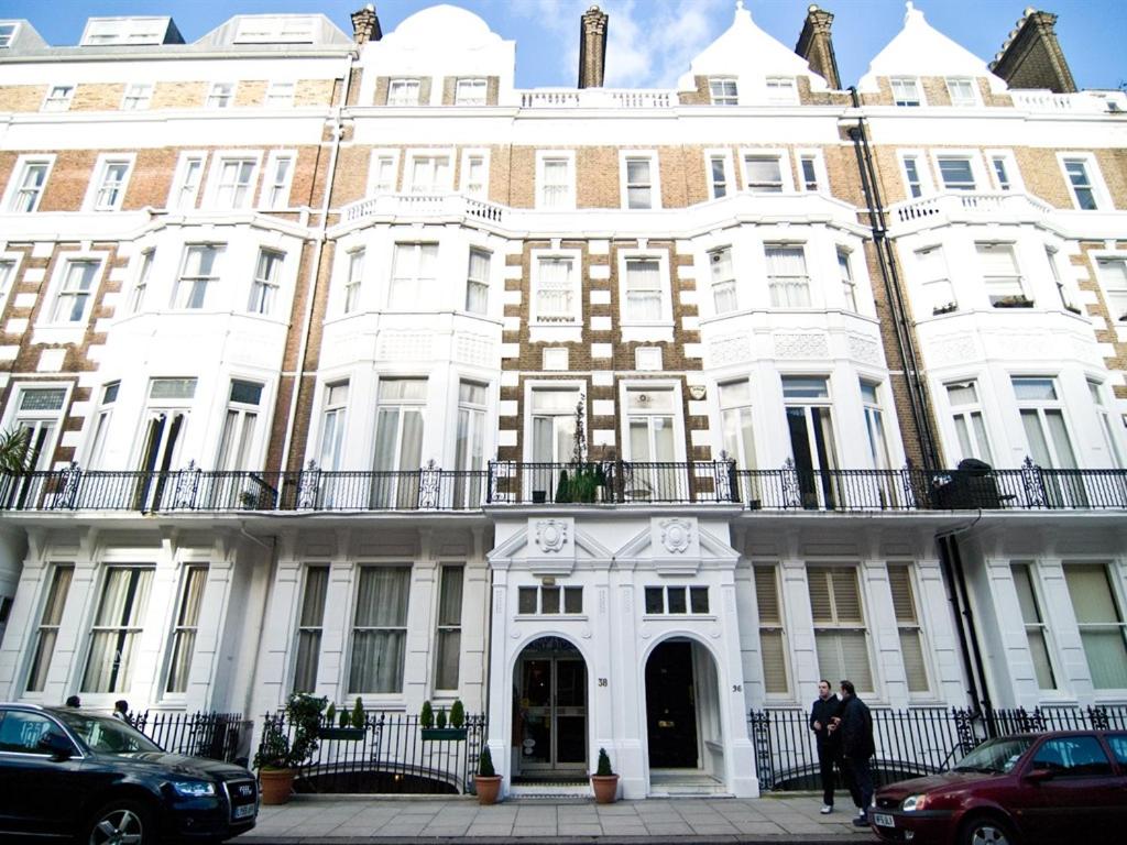 伦敦圣西缅酒店的一座白色的大建筑,前面有人站在