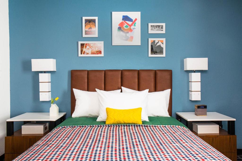 霍姆斯泰德Uptown Suites Extended Stay Miami FL – Homestead的一间卧室设有蓝色的墙壁和一张黄色枕头的床