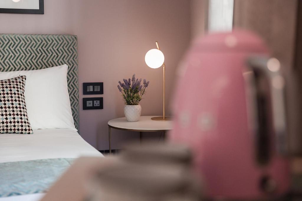 圣朱利安斯123 MAINSTREET boutique hotel的一间卧室配有一张床和一张带台灯的桌子