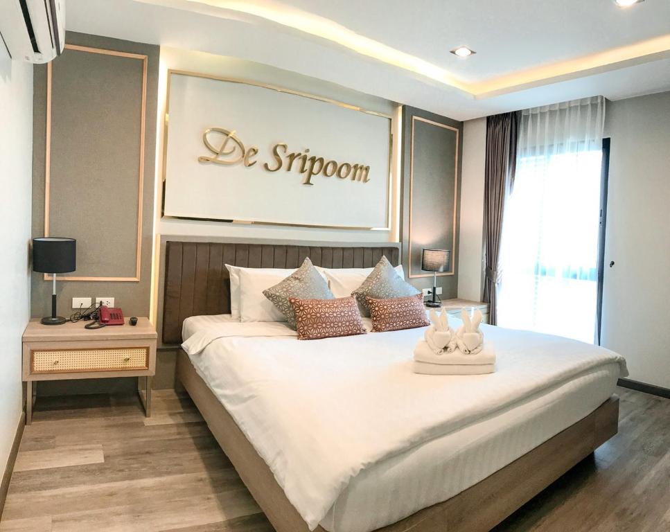 清迈Hotel De Sripoom -SHA Extra Plus的卧室配有一张白色大床,墙上有标志