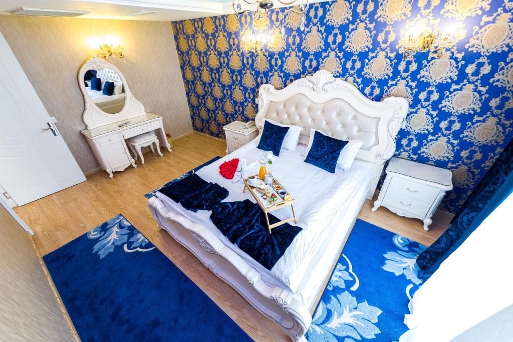 克拉约瓦鹤林中心酒店的卧室配有白色大床和蓝色的墙壁