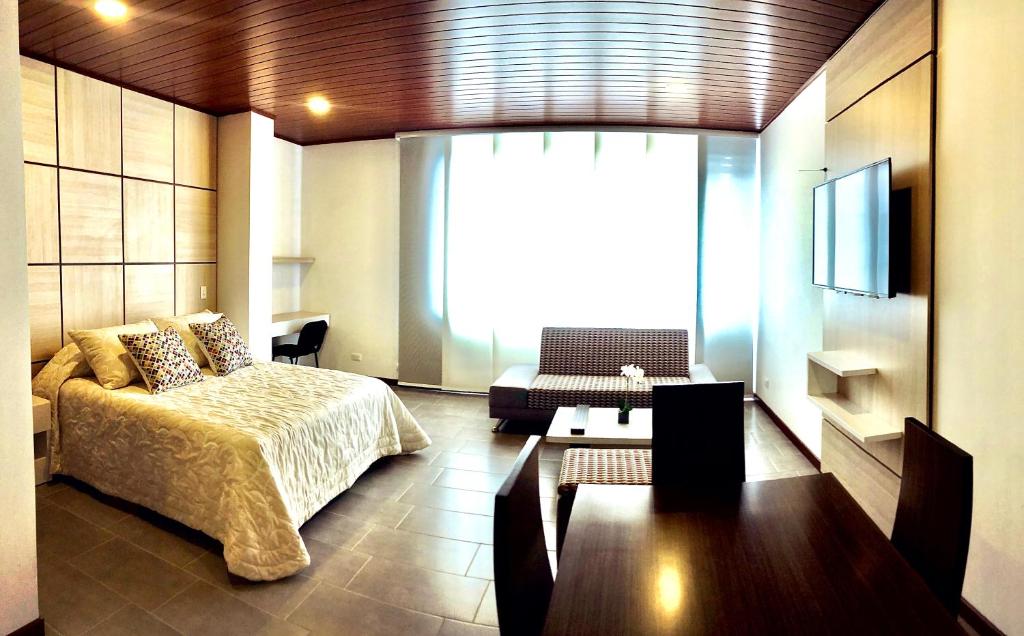 波哥大Apartamentos Edificio San Miguel Bogotá的一间卧室配有一张床、一张沙发和一台电视。