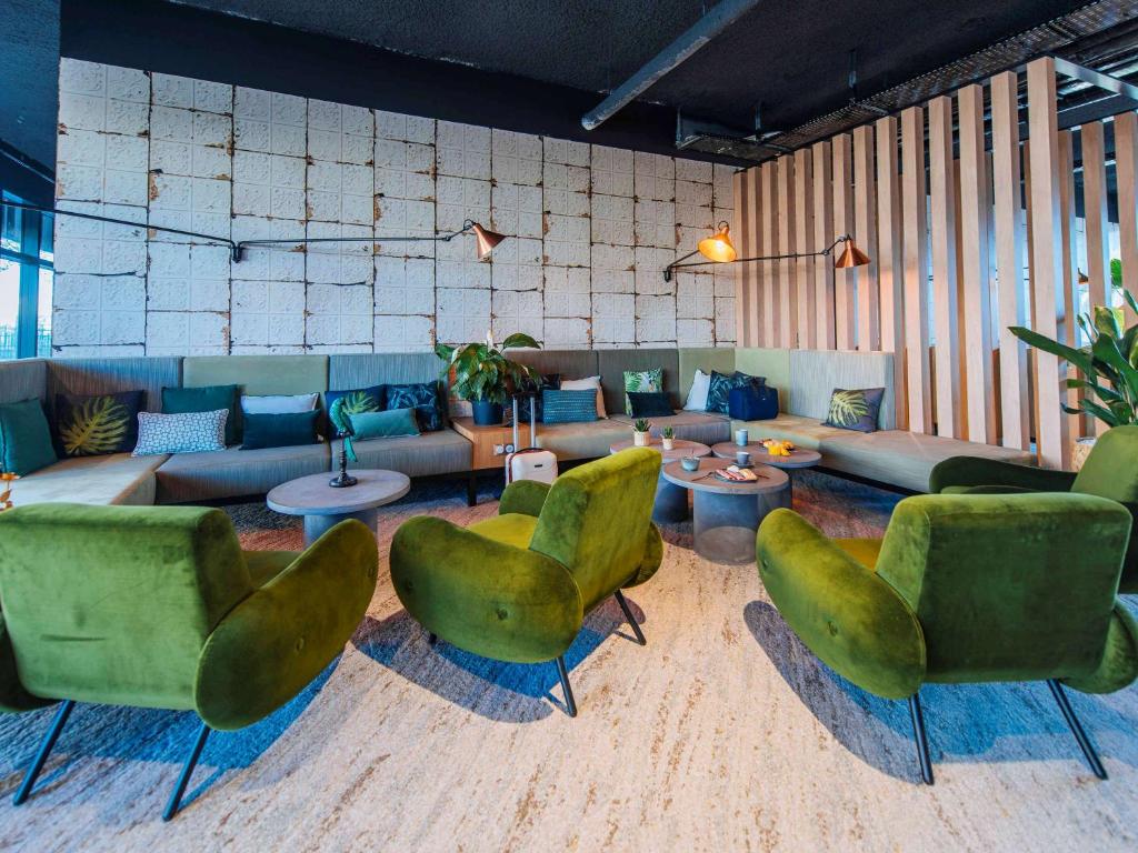 鲁昂Ibis Styles Rouen Centre Rive Gauche的客厅配有绿色椅子和沙发