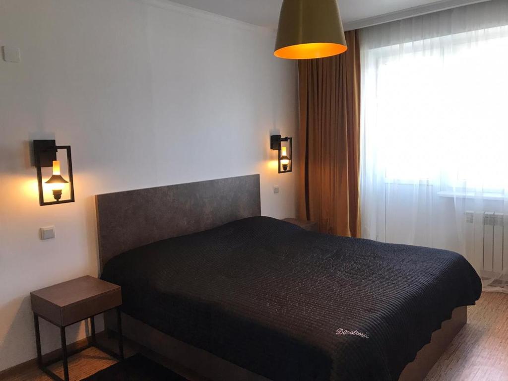 阿拉木图Стильная и уютная однокомнатная квартира в г.Алматы的一间卧室设有一张黑色的床和一个窗户。
