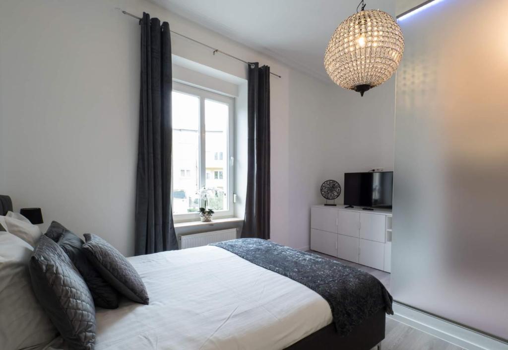 卢森堡EXECUTIVE DOUBLE ROOM WITH EN-SUITE in GUEST HOUSE RUE TREVIRES R3的一间卧室配有一张床、一台电视和吊灯。