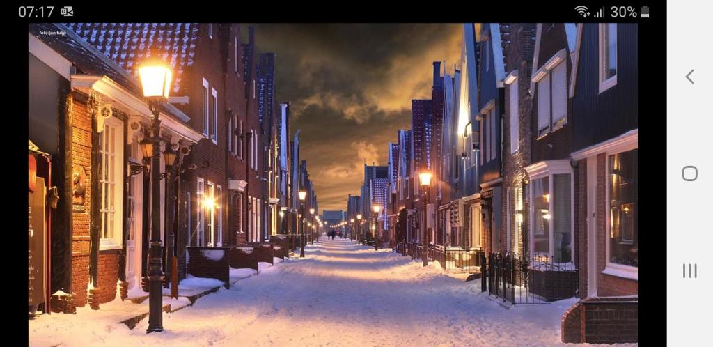 福伦丹B&B CaSandra的夜间有雪覆盖的街道,有建筑物和街道灯