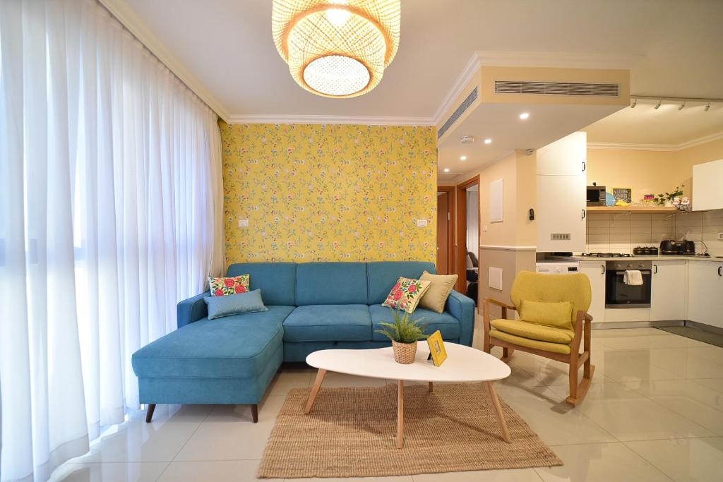 提比里亚YalaRent Migdalor Boutique Hotel Apartments with Sea Views Tiberias的客厅配有蓝色的沙发和桌子