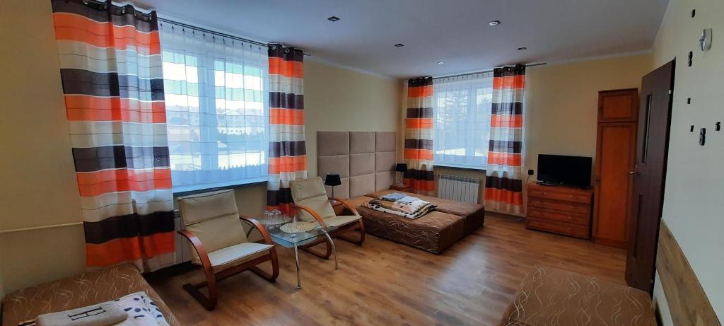 塔尔诺布热格Noclegi-Zajazd"Mieszko"的客厅配有色彩缤纷的窗帘和桌椅