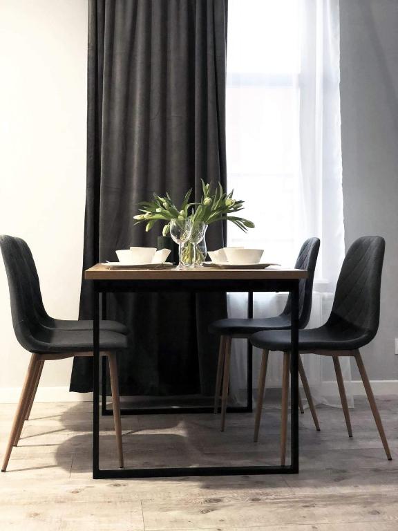 埃尔布隆格Apartament Stare Miasto的一张桌子,上面有黑椅子和一个花瓶,上面有植物