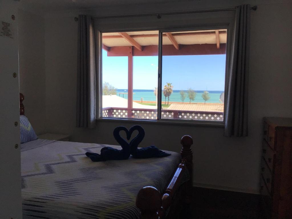 德纳姆最佳海滩别墅的一间卧室,配有一张床,窗户上带有心灵