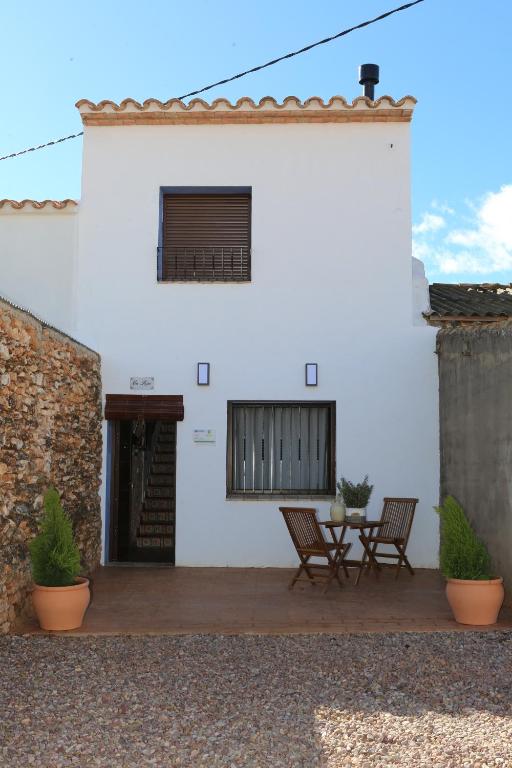 UserasCasa Rural Mas dels Fumeros的白色的房子,庭院里配有两把椅子和一张桌子