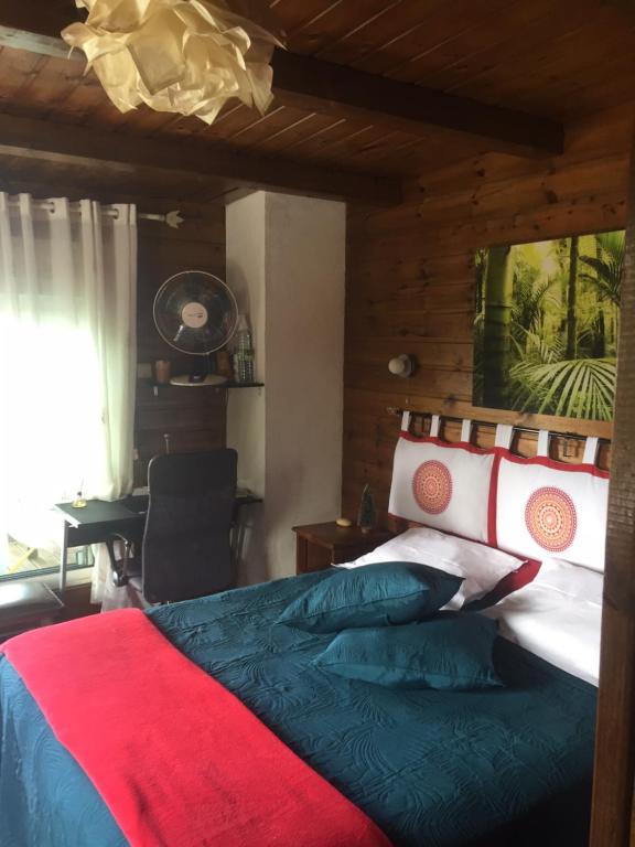 勒唐蓬COEUR CREOLE的一间卧室配有一张带红色和蓝色毯子的床