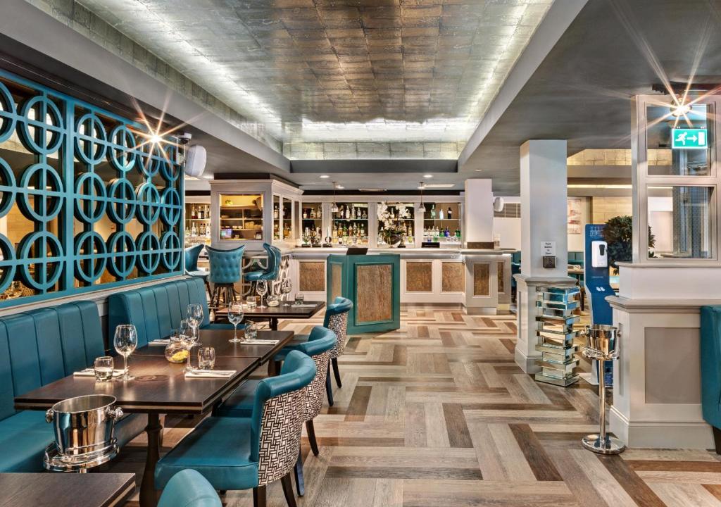 哈罗盖特西园酒店的餐厅设有木桌和蓝色椅子