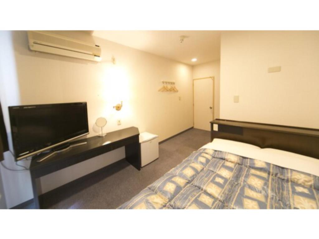 德岛Self inn Tokushima kuramoto ekimae - Vacation STAY 19487v的配有一张床和一台平面电视的酒店客房