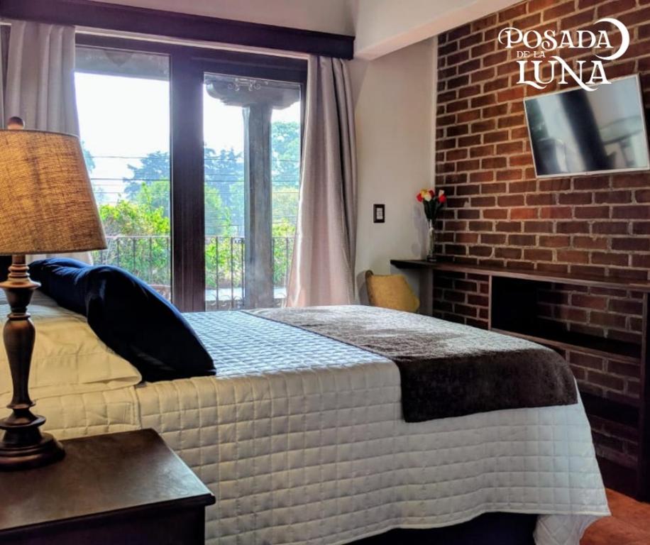 危地马拉安地瓜月光女神酒店的一间卧室设有一张床和砖墙