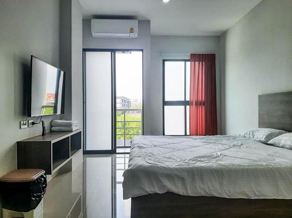 曼谷AFP Residence Hotel的一间卧室设有一张床、一台电视和一个窗口。
