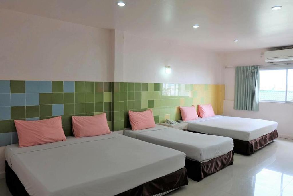 合艾Center Mansion at Hatyai的客房配有两张带粉红色枕头的床。