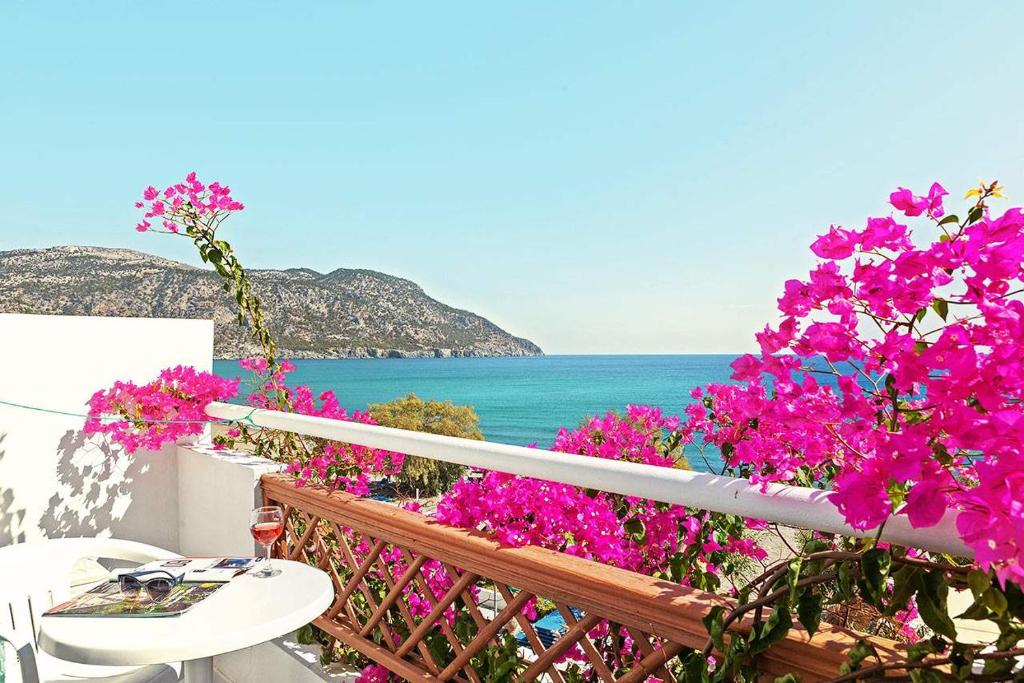 卡尔帕索斯MINOS BEACH KARPATHoS的阳台拥有粉红色的鲜花,享有海景。
