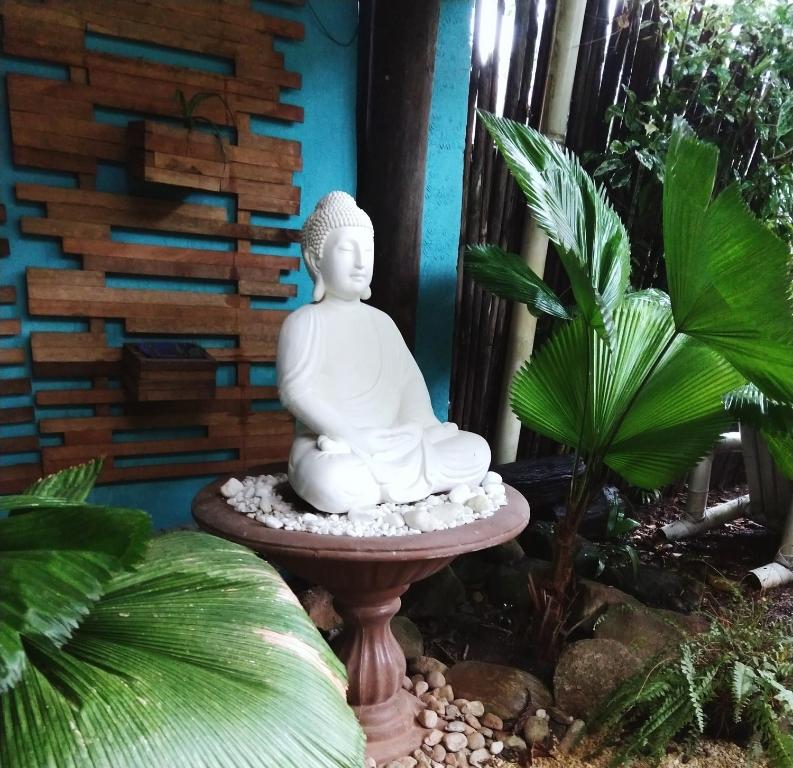 马蒂尼奥斯Pousada Gaucha Caiobá的坐在花园中的一个站台上的白佛像