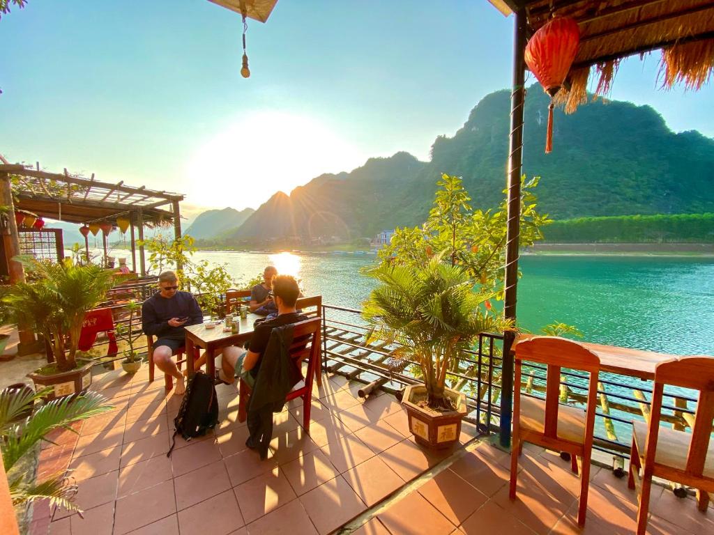 峰牙Phong Nha Coco Riverside的一群人坐在水边的桌子上
