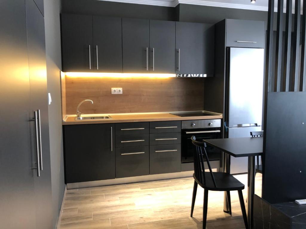 亚历山德鲁波利斯Stamatina’s Luxury Apartments (central)的厨房配有黑色橱柜、桌子和水槽。