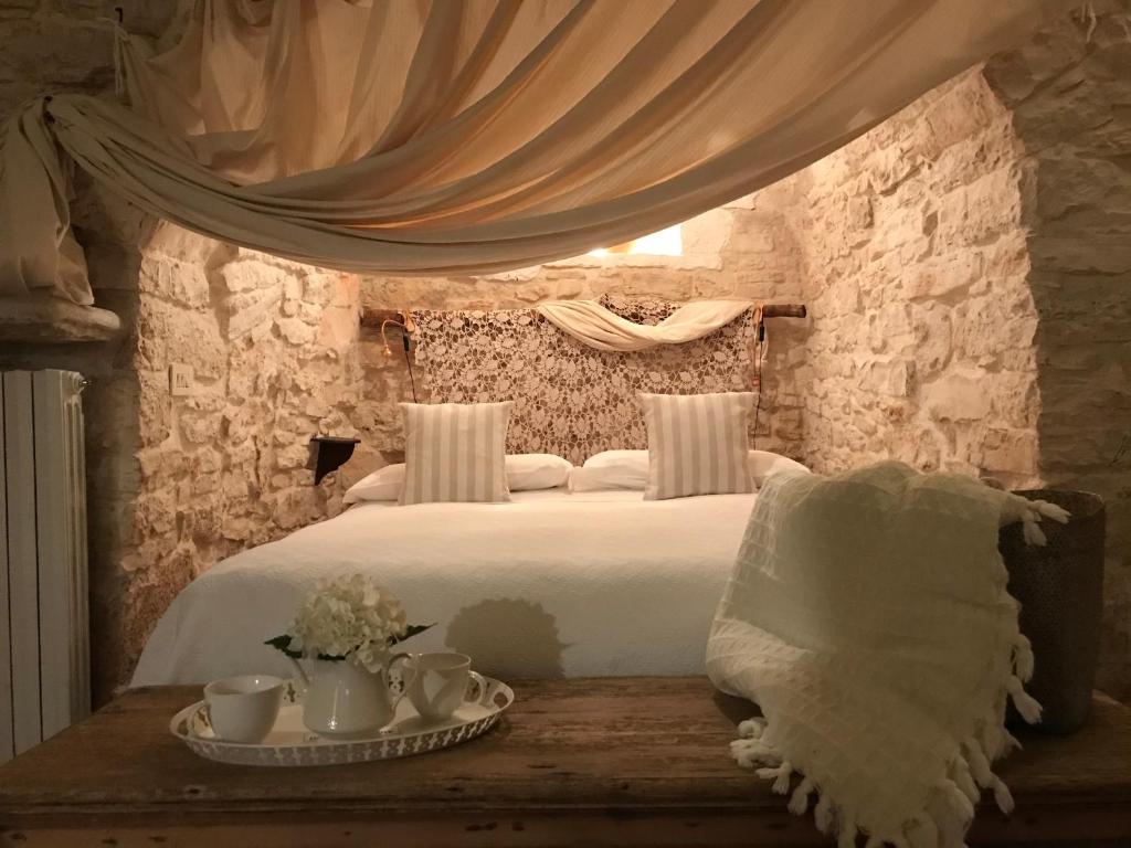 阿尔贝罗贝洛Trulli Aria di Casa的卧室配有白色的床和带杯子的桌子