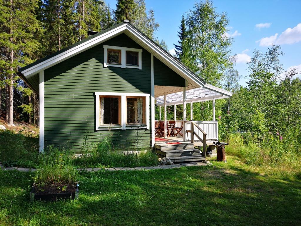 SavonrantaLakeside cottage Metsäranta Savonranta的草坪上带门廊的绿色小房子