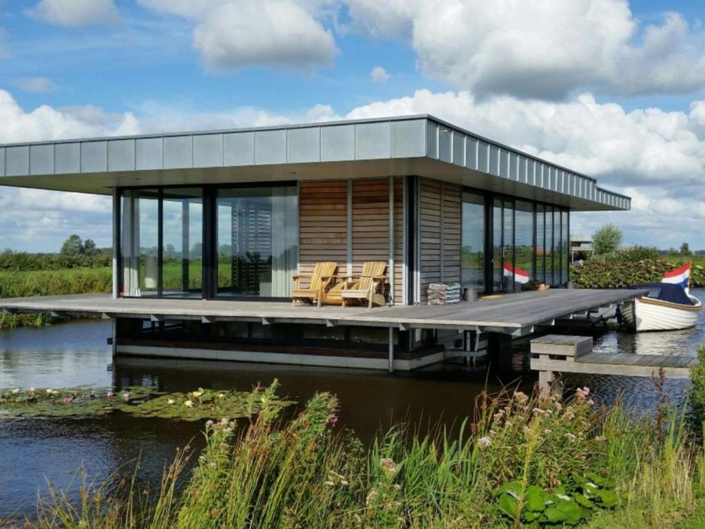 GoëngahuizenLovely house boat in Goengahuizen with sauna的水面上的房子,有码头