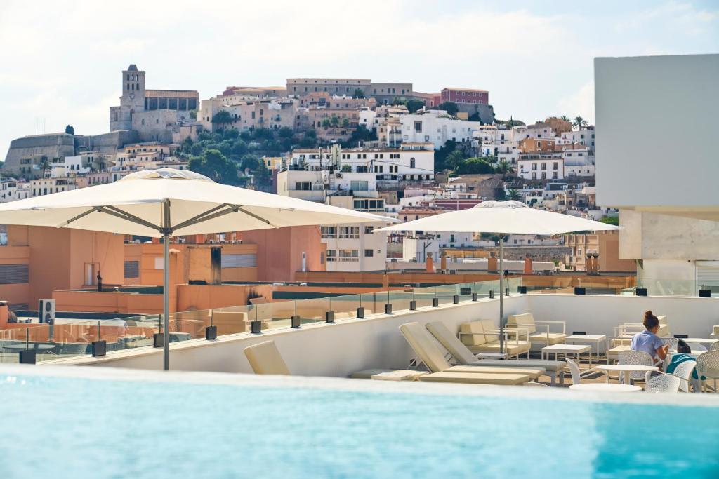 伊维萨镇El Puerto Ibiza Hotel Spa的一座带遮阳伞的建筑屋顶游泳池