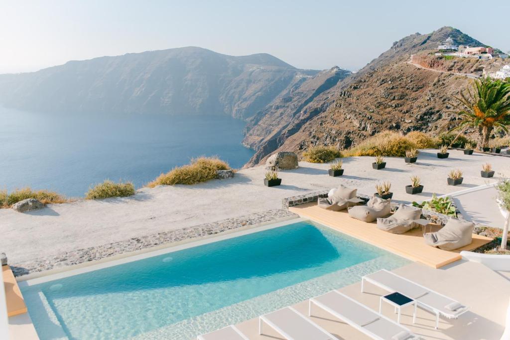 易莫洛林Rocabella Santorini Hotel & Spa的一个带椅子的游泳池,享有海景