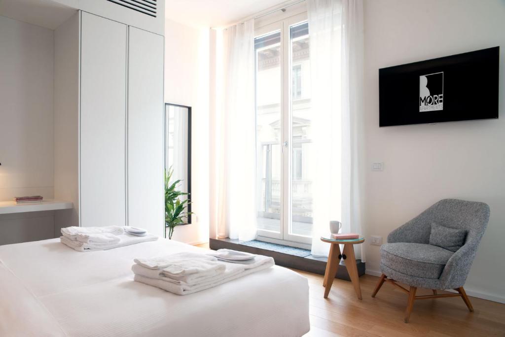 米兰BMORE Apartments Duomo的卧室配有床、椅子和窗户。