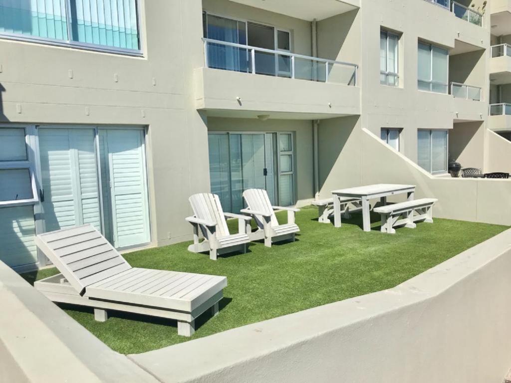 布鲁堡史特兰Voir la Mer - Blouberg Beach的一座带草坪椅和桌子的庭院以及一座建筑
