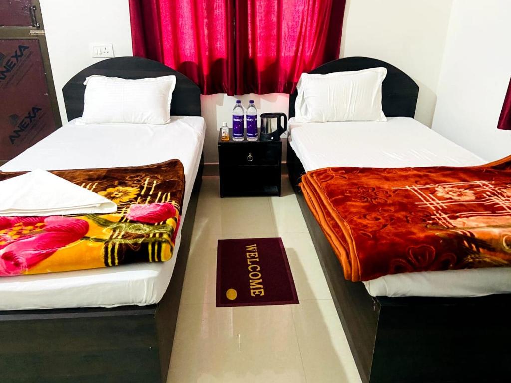 菩提伽耶Gaurav guest house的配有红色窗帘的客房内的两张床