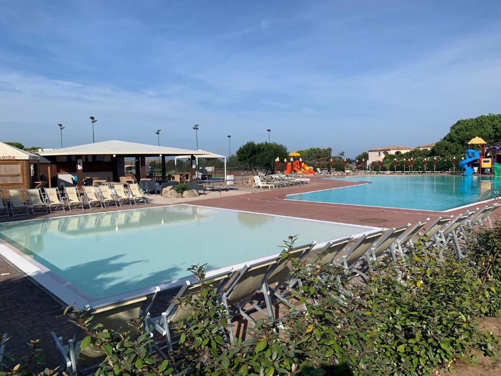 阿列恩图Club Esse Gallura的一个带椅子的大型游泳池和游乐场