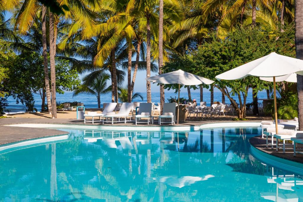 萨尤利塔AzulPitaya Beach Front Hotel in Sayulita的一个带椅子和遮阳伞的游泳池以及大海