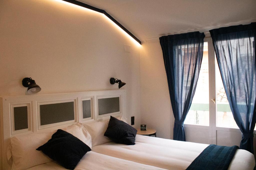 哈卡Hotel Alda Jolio Jaca的卧室配有带黑色枕头的白色床和窗户。