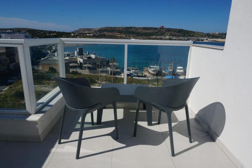 梅利哈Sea View Penthouse Mellieha Bay的海景阳台上的桌椅