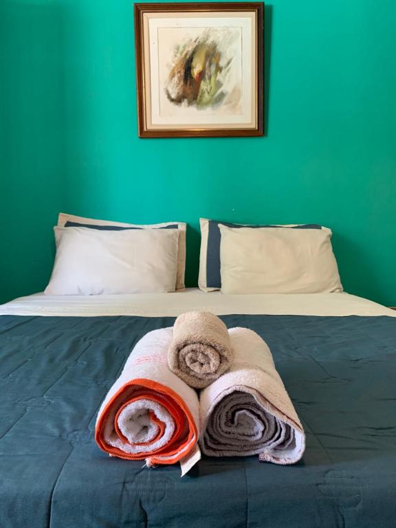马瑙斯Amanda Suites的一张带毛巾的床和绿色的墙壁